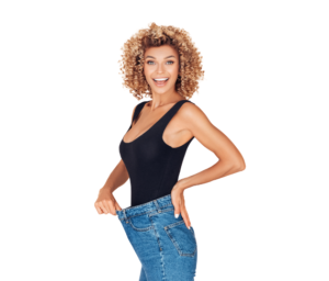 Woman showing weight loss in jeans, smiling.